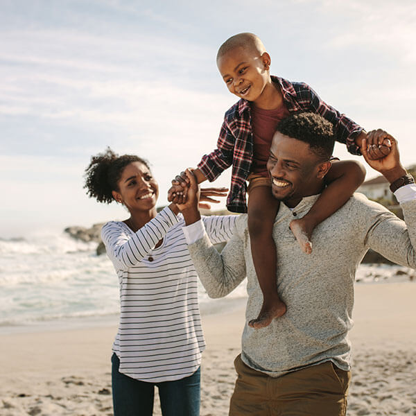 parents carrying their son on their shoulders at beach