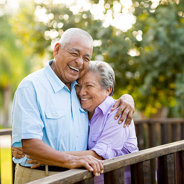 senior couple laughing together on a bridge