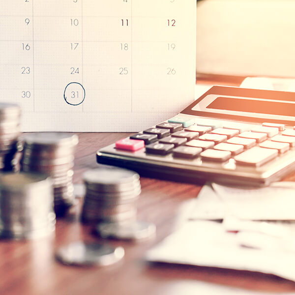 coins and calculator on a desk, calendar in the background