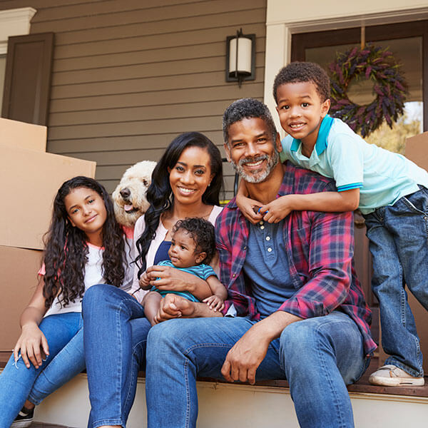 family with children and dog outside house on moving day