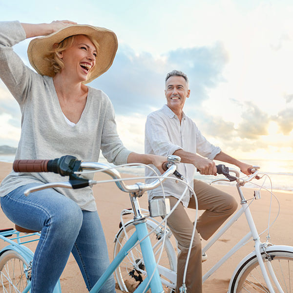 mature couple cycling on the beach